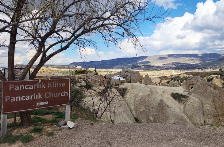 Pancarlık Kilise tabelası ve arka planda Kapadokya’nın kayalık Pancarlık Vadisi manzarası